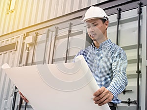 Portrait of an engineer man with helmet looking paper plans at construction site, Project engineer