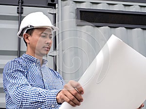 Portrait of an engineer man with helmet looking paper plans at construction site, Project engineer