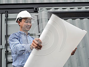 Portrait of an engineer man with helmet looking paper plans at construction site, Project engineer