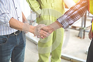 Portrait of engineer people shaking hands after finish successful project at construction site