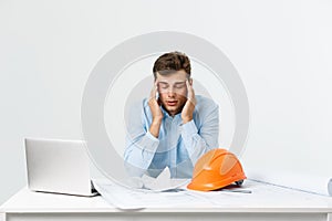 Portrait of engineer stress holding his head with hand sitting at the table and feel headache in the office on isolated