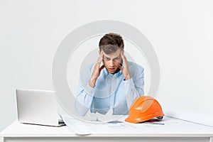 Portrait of engineer stress holding his head with hand sitting at the table and feel headache in the office on isolated