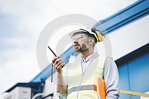Portrait of engineer using walkie-talkie talking in production site