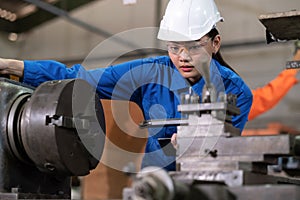 Portrait of engineer worker woman wearing uniform and PPE holding tablet and looking at machine in the factory. Preventive