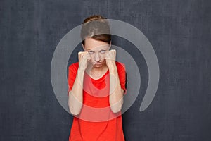 Portrait of enraged dissatisfied girl holding fists clenched