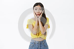 Portrait of enthusiastic excited and intrigued charming female shopoholic in yellow trendy t-shirt folding lips from