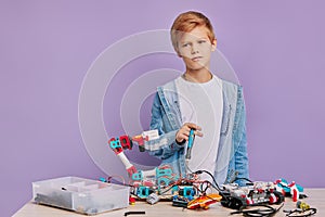 Portrait of enthusiastic kid boy concerned with assembling robots in engineering club