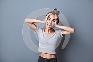 Portrait of an enthusiastic young woman screaming with joy over grey wall background