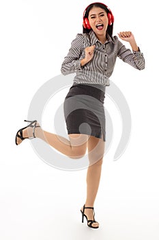 Portrait of an enthusiastic young woman wearing red headphones standing with joyful gestures isolated on white background.