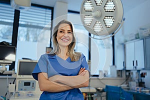 Portrait of ER doctor in hospital working in emergency room. Portrait of beautiful nurse in blue uniform, crossed arms