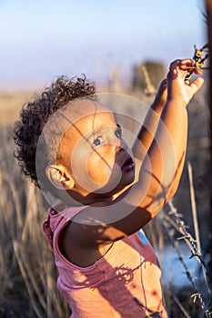 A portrait of an ethiopian mixed etnicity interracial child toddler holding a barbed wire fence looking worried and sorrowful.