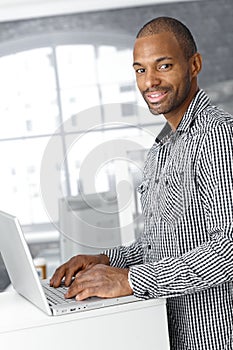 Portrait of ethnic office worker with laptop