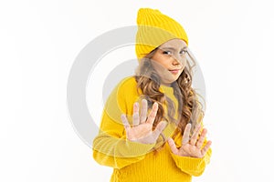 Portrait of european attractive girl in a yellow hat shows discontent with hands on a white background with copyspace