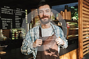 Portrait of european barista guy working in street cafe or coffeehouse outdoor