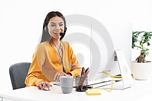 Portrait of european hotline assistant woman wearing microphone headset speaking with customer by phone in office