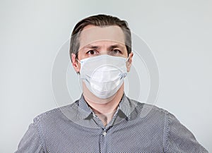 Portrait of an European man in one-use mask, looking at camera, grey background