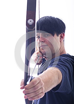 Portrait of a European young man, 21 years old, against a white background, spans a takedown recurved bow and aims
