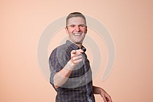 Portrait of european young man, laughing, pointing with finger at someone.