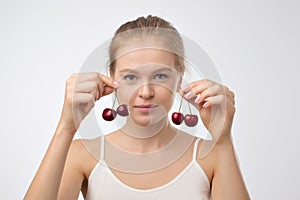 Portrait of european young woman holding red cherry.