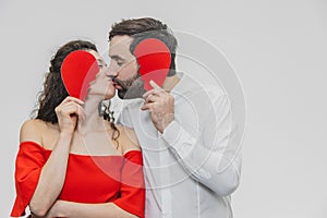 Portrait of an Excessive Couple. Hold two pieces of carded paper and kiss. Women dressed in red men`s dresses in a white