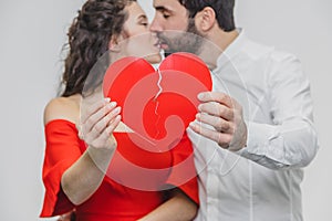 Portrait of an Excessive Couple. Hold two pieces of carded paper and kiss. Women dressed in red men`s dresses in a white