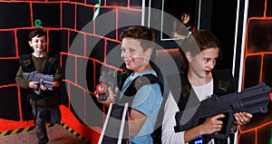 excited teen boy and girl aiming laser gun at other players