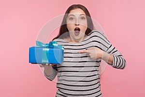 Portrait of excited amazed woman in striped sweatshirt pointing at birthday gift and looking surprised photo