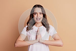 Portrait of excited astonished girl hold palms plead sign isolated on beige background