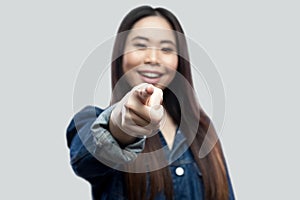 Portrait of excited beautiful brunette asian young woman in casual blue denim jacket with makeup standing toothy smiling and