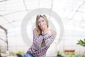 Portrait of excited beautiful woman covering her mouth with hands trying to stop giggling. Pretty stylish amazed young woman