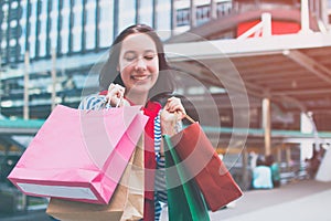 Portrait of an excited beautiful young girl wear shirt holding many shopping bags and smile. With copy space.
