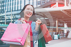 Portrait of an excited beautiful young girl wear shirt holding many shopping bags and smile. With copy space.