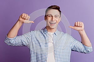 Portrait of excited boasting guy open mouth indicate thumb himself on purple background