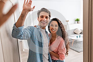 Happy couple inviting people to enter home, giving high five