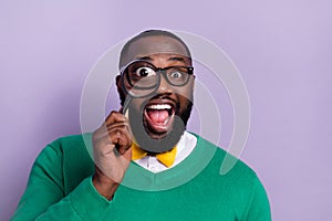 Portrait of excited crazy overjoyed young man see through magnifying glass isolated on violet color background