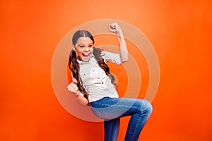 Portrait of excited ecstatic little girl win sport contest shout yeah raise fists feel content wear casual style clothes