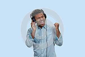 Portrait of excited emotional Indian man listen to music in headphones.