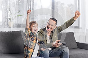 portrait of excited father and son playing video game together