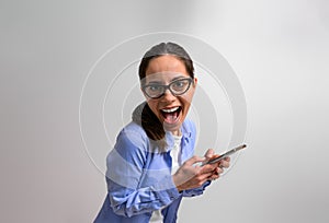 Portrait of excited female entrepreneur shouting cheerfully and messaging online on smart phone. Ecstatic businesswoman wearing