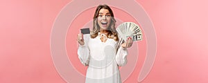 Portrait of excited happy good-looking blond girl in white dress, winning money, placed good bet, made deal, holding