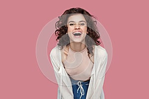 Portrait of excited happy positive beautiful brunette young woman with curly hairstyle in casual style standing, looking at camera