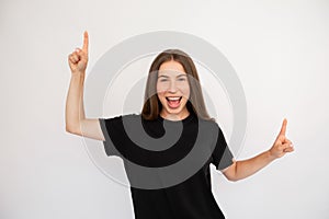 Portrait of excited happy young woman pointing upwards