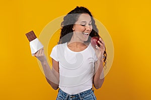 Portrait of Excited Lady Holding Chocolate And Biting Apple