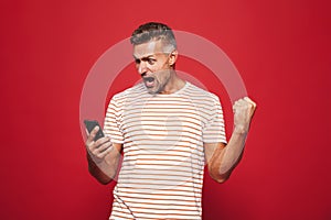 Portrait of an excited man standing over red background