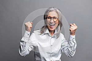 Portrait of excited overjoyed businesswoman standing with raised fists and shouting yeah, I'm winner, rejoicing