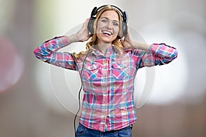 Portrait of excited smiling young woman with headphones listening to music.