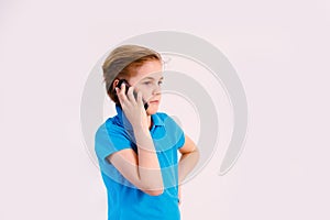 Portrait of excited stylish boy wearing blue t-shirt, holding mobile phone isolated over white background