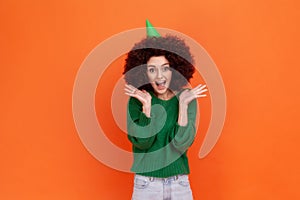 Portrait of excited woman with Afro hairstyle wearing green casual style sweater and party cone