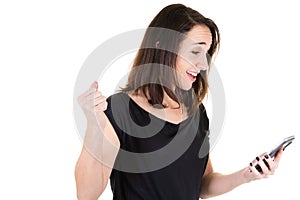 Portrait of an excited woman in black reading good news in a smart phone on white wall background