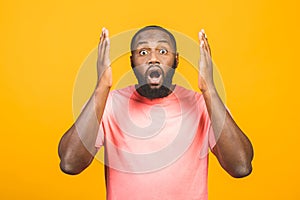 Portrait of excited young African American male screaming in shock and amazement holding hands on head. Surprised black hipster